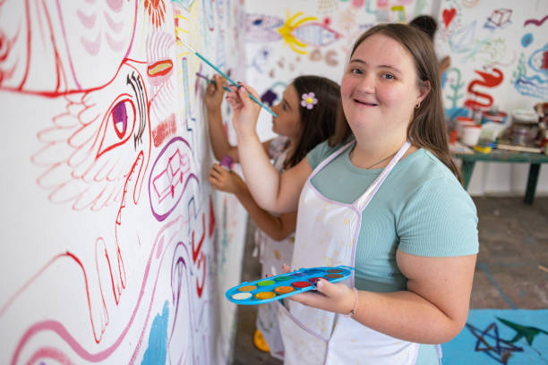 Young woman with Down syndrome painting a colorful mural in an art day program